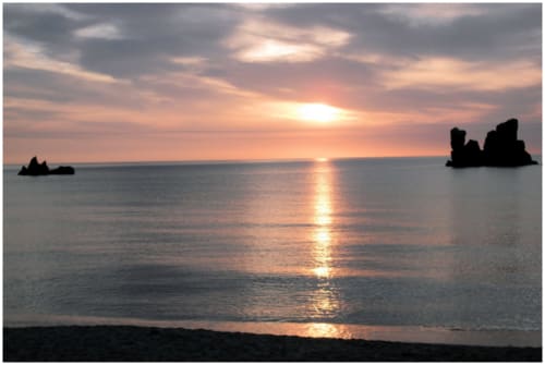 Tramonto sul mare a Resort Baia Cea a Bari Sardo, con rocce silhouette contro il cielo dorato