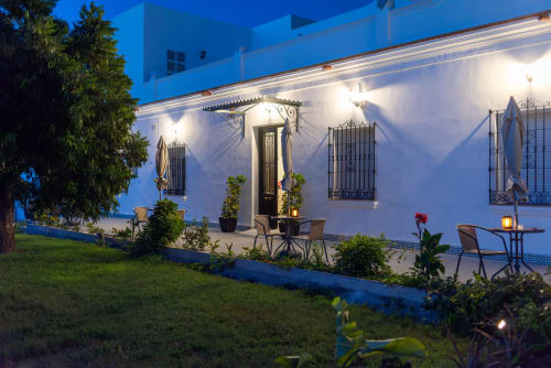 Hotel Boutique Alcazaba Salobreña al atardecer, fachada blanca con detalles azules, patio iluminado con asientos