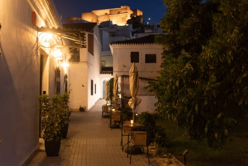 Patio nocturno del Hotel Boutique Alcazaba Salobreña con edificios encalados, faroles iluminados y vistas del castillo en Granada
