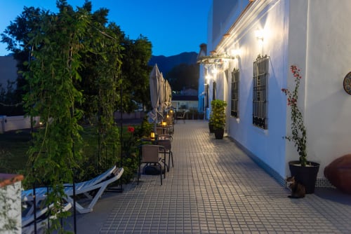 Patio vespertino del hotel Alcazaba Salobreña con pérgola cubierta de hiedra, fachada blanca y vistas a la montaña