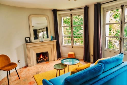 Salón luminoso en Villa Raspail con sofá azul, chimenea, vistas al jardín y decoración moderna en Ivry-sur-Seine