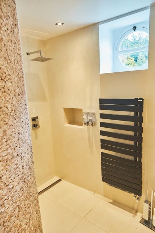 Cuarto de baño moderno con mosaicos de baldosas de terracota, toallero negro y ventana redonda en Villa Raspail B&B, Ivry-sur-Seine