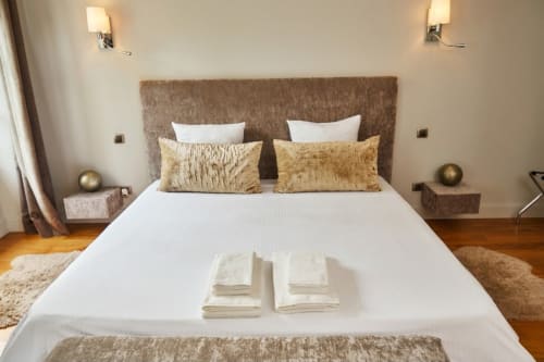 Dormitorio elegantemente decorado en Villa Raspail B&B en Ivry-sur-Seine con cabecero tapizado, ropa blanca y detalles dorados