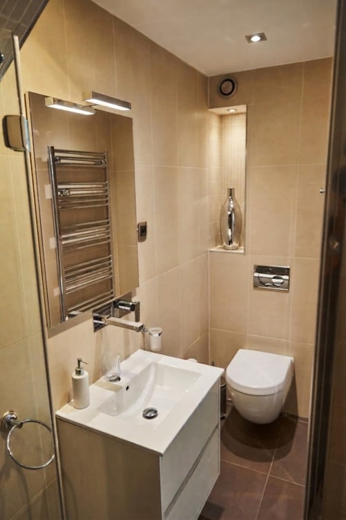 Baño moderno en Villa Raspail B&B con lavabo blanco, inodoro mural, toallero calefactor y ducha a ras de suelo