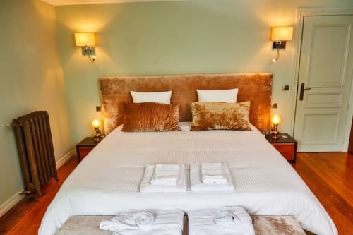 Dormitorio elegante en Villa Raspail B&B en Ivry-sur-Seine con cabecero de terciopelo dorado, ropa blanca, lámparas bronce y madera