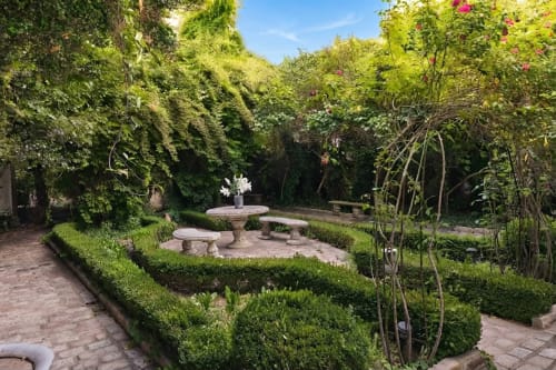 Patio exuberante en Villa Raspail con fuente, setos, enredaderas florecidas y terraza de ladrillo en Ivry-sur-Seine