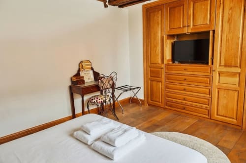 Elegante dormitorio en Villa Raspail B&B en Ivry-sur-Seine con armario de madera, televisor de pantalla plana, escritorio de época y ropa de cama blanca