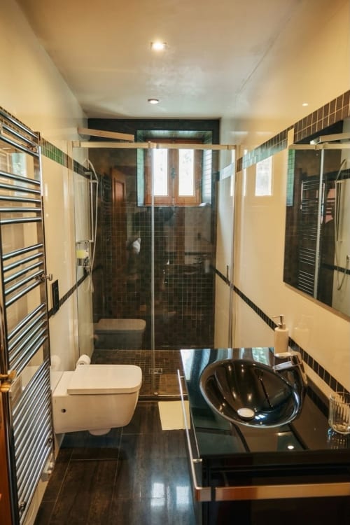 Baño moderno en Villa Raspail B&B con ducha de azulejos negros, inodoro blanco y lavamanos negro en Ivry-sur-Seine