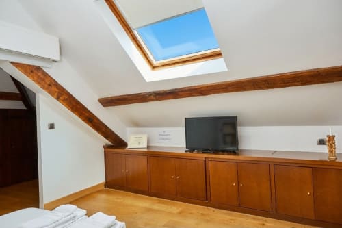 Dormitorio luminoso en buhardilla de Villa Raspail con claraboya, vigas de madera, TV pantalla plana, armario de madera y suelo de madera