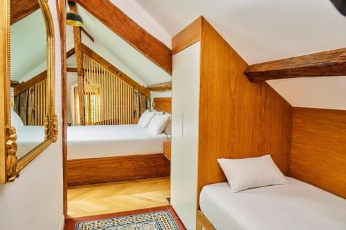Cama con dosel de madera y ropa de cama blanca en el dormitorio Villa Raspail, Ivry-sur-Seine