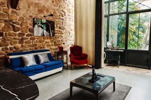 Sala de estar moderna en Villa Raspail con sofá azul, sillón rojo y muros de ladrillo expuesto con vistas al jardín