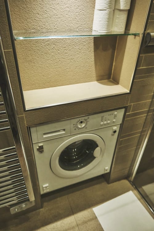 Lavadora empotrada con estante de vidrio encima en el baño del apartamento Villa Raspail, Ivry-sur-Seine