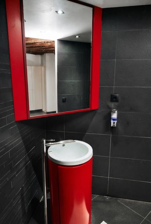 Baño moderno con tocador rojo y azulejos negros en el apartamento Villa Raspail, Ivry-sur-Seine