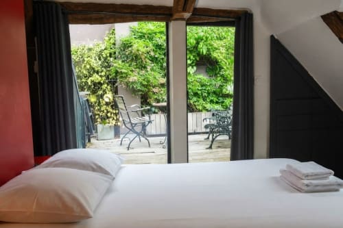 Dormitorio moderno con ropa de cama blanca, vista al jardín a través de puertas de cristal, Villa Raspail B&B en Ivry-sur-Seine