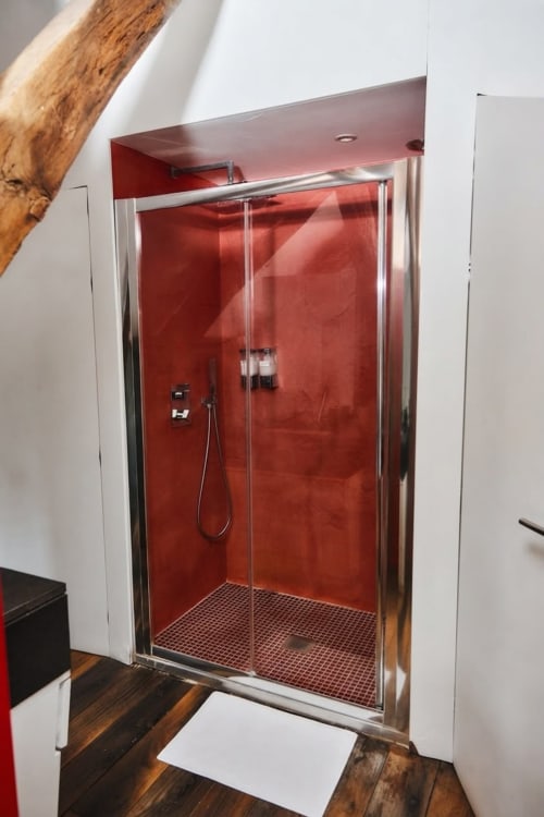 Moderno cerramiento de ducha rojo con puertas de cristal y marco metálico en el baño del apartamento Villa Raspail, Ivry-sur-Seine