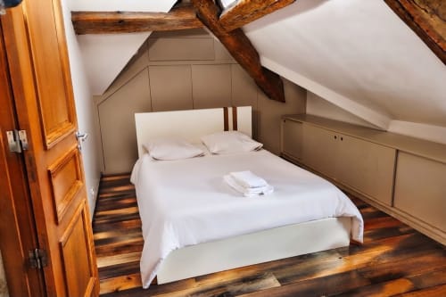 Acogedora habitación en buhardilla de Villa Raspail con vigas de madera, ropa de cama blanca y decoración rústica en Ivry-sur-Seine