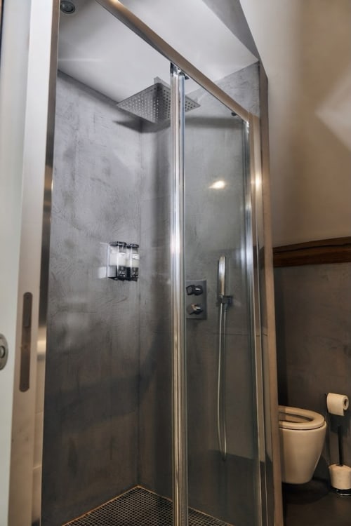 Ducha moderna con paredes de azulejos grises y alcachofa de lluvia en el apartamento Villa Raspail en Ivry-sur-Seine, Francia