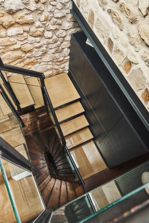 Escalera de caracol con peldaños de madera y barandilla de metal negro en apartamento Villa Raspail, Ivry-sur-Seine