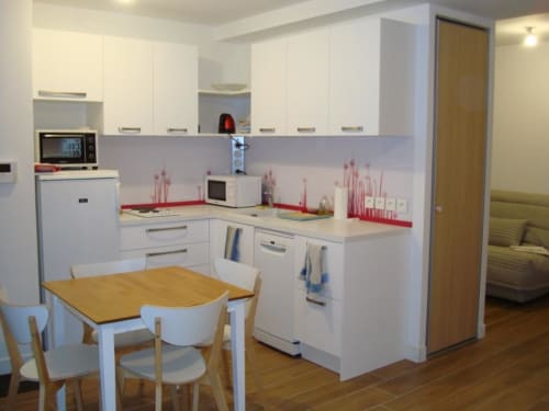 Cuisine blanche moderne avec table à manger dans l'appartement de Vars, équipée d'un micro-ondes et d'un lave-vaisselle
