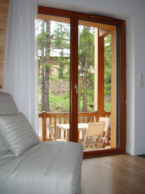 Portes-fenêtres modernes d'un balcon donnant sur un paysage forestier à Vars, France