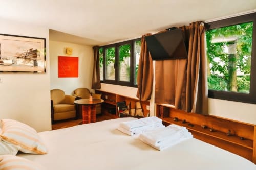 Dormitorio moderno con vistas al jardín en Villa Raspail, Ivry-sur-Seine. Cama, zona de estar, TV y acceso privado