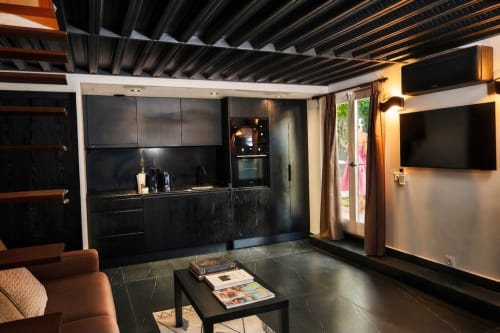 Cocina moderna negra con TV de pantalla plana y vistas al jardín en Villa Raspail, Ivry-sur-Seine