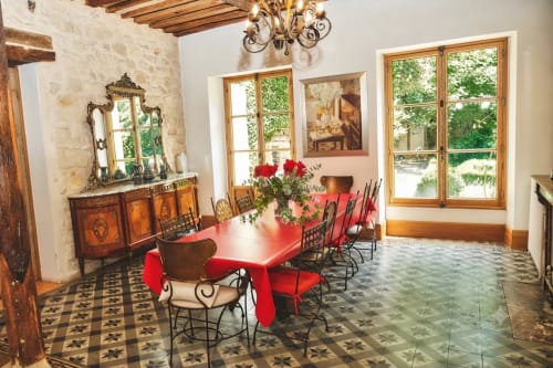 Salle à manger du gîte Villa Raspail à Ivry-sur-Seine avec table rouge, miroir ouvragé, murs de pierre et vue sur le jardin