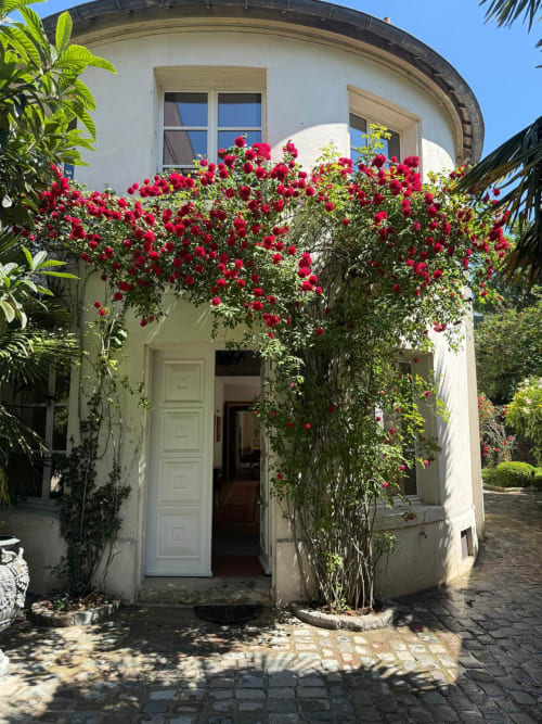 Entrée de cottage blanc avec des roses cramoisies éclatantes à la Villa Raspail B&B à Ivry-sur-Seine