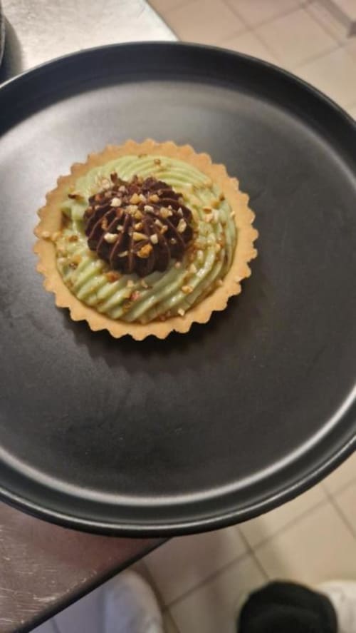 Élégant cupcake à la pistache avec ganache de chocolat noir et paillettes dorées au Perroquet Bleu, France