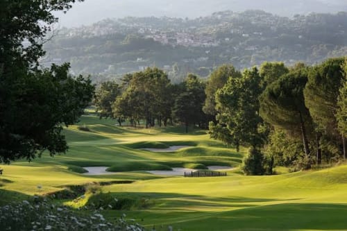 Parcours de golf verdoyant avec plans d'eau et allées bordées d'arbres surplombant les maisons du coteau de Cagnes-sur-Mer à STAYnGOLF