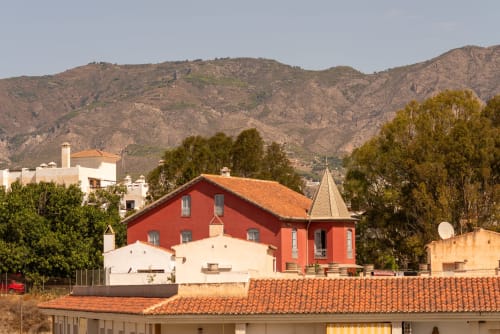 Edificio hotelero rojo y blanco con tejados de tejas naranjas con vistas a las montañas en Salobreña, Granada