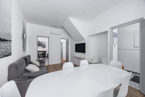 Apartamento moderno em A Lodge in Blue, Aveiro com mesa de jantar, cadeiras brancas e área de estar cinzenta