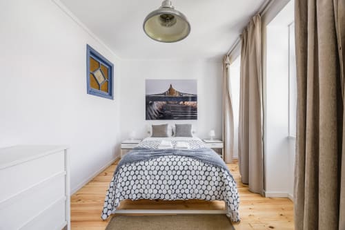 Quarto luminoso em A Lodge in Blue, Aveiro, com cama queen, roupa de cama geométrica, piso de madeira e arte costeira
