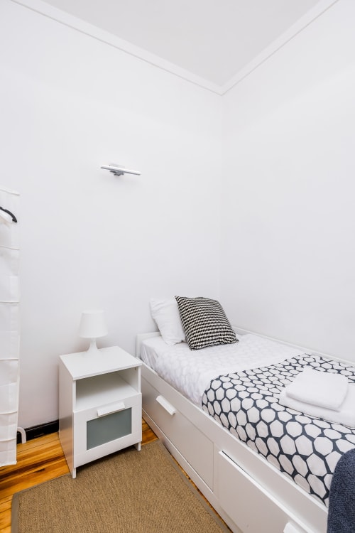 Quarto minimalista na A Lodge in Blue com cama branca, almofadas geométricas e piso de madeira em Aveiro