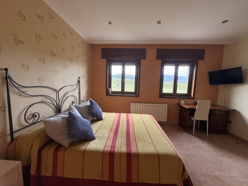 Espacioso dormitorio doble en Casa Aida con vistas al mar, cama de hierro, ropa de cama a rayas, TV y ventanas con vistas a la costa