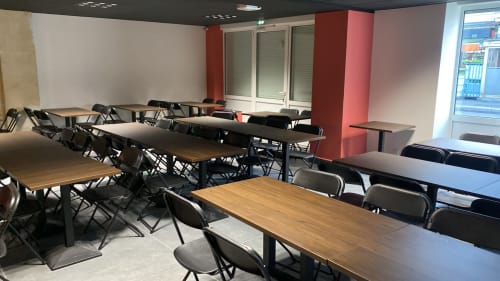 Salle de réception moderne à la Villa Raspail Ivry-sur-Seine avec tables en bois, chaises noires, colonnes rouges et piste de danse séparée
