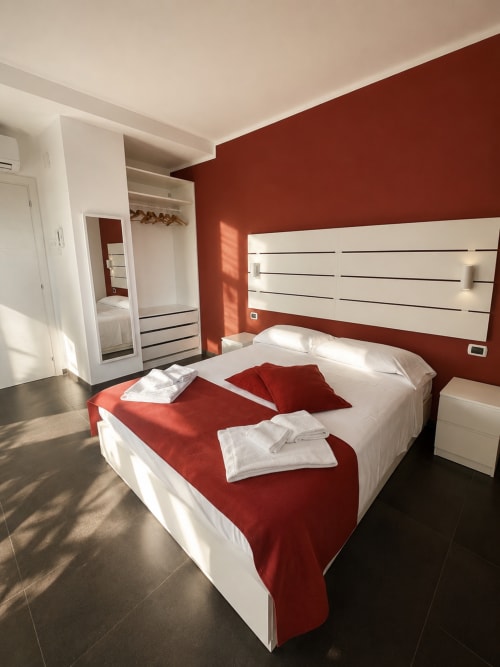 Camera moderna alle Soave Rooms B&B di Napoli con parete rossa, letto bianco e arredi contemporanei