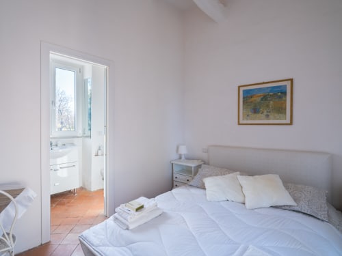 Camera luminosa al Ponteronico Resort di Sessa Aurunca con letto matrimoniale, cuscini bianchi, bagno en-suite e paesaggio incorniciato