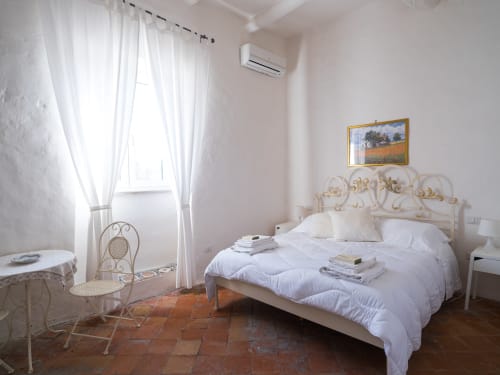 Camera luminosa con letto ornato, biancheria bianca, pavimento in cotto e aria condizionata al Ponteronico Resort, Sessa Aurunca