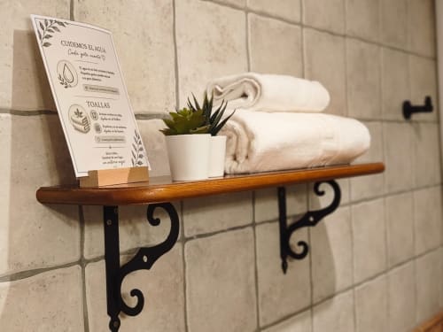 Wooden shelf in bathroom with rolled towels, succulent plant, and water conservation sign at Hospedería Puerta a los