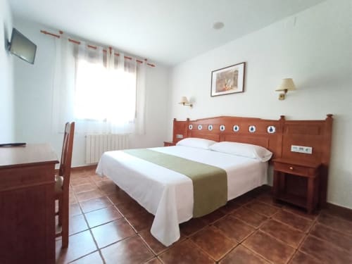 Habitación doble estándar en Hospedería Puerta a los Cahorros de Monachil con cama de madera, escritorio, TV y vistas a las montañas