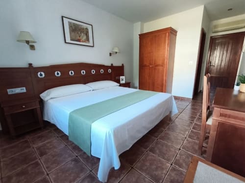 Spacious double bedroom at Hospedería Puerta a los Cahorros in Monachil with wooden furnishings and mountain views