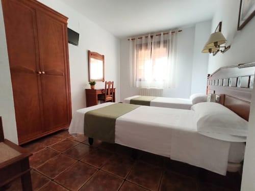 Standard double bedroom at Hospedería Puerta a los Cahorros in Monachil with twin beds, wooden wardrobe, and mountain views