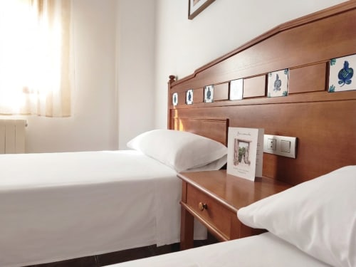 Cozy double bedroom at Hospedería Puerta a los Cahorros hostel in Monachil with wooden headboard and white bedding