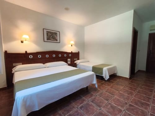 Habitación triple en Hospedería Puerta a los Cahorros de Monachil con cama de madera, cama individual y suelos de terracota