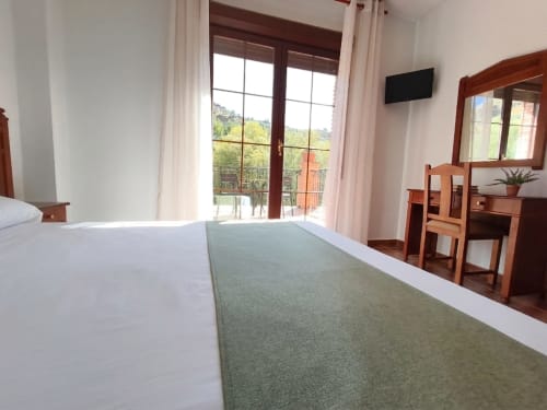 Amplia habitación doble con terraza en Hospedería Puerta a los Cahorros, con vistas a la montaña, muebles de madera y diseño moderno