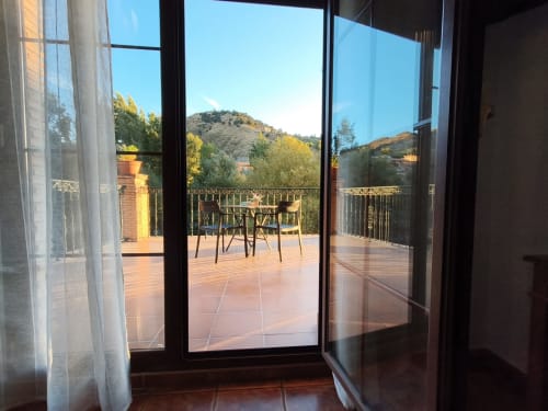 Monachil hostel room terrace with mountain views, furnished seating area, and river valley landscape in Spain