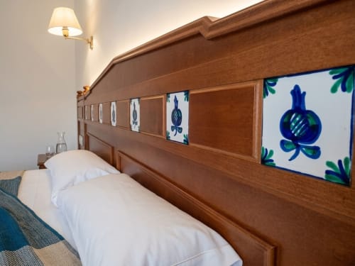 Acogedora habitación en albergue en Monachil con cabecero de madera decorado con azulejos cerámicos azules y ropa de cama blanca