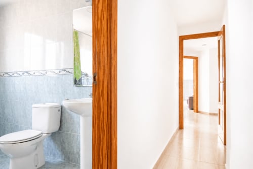 Pasillo y baño moderno en apartamento Riurau Home, Calpe con puertas de madera y detalles en azulejos azules