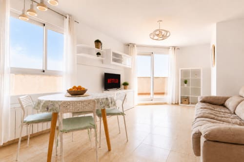Luminoso apartamento diáfano en Calpe con zona de comedor, TV Netflix, sofá beige y vistas a las montañas